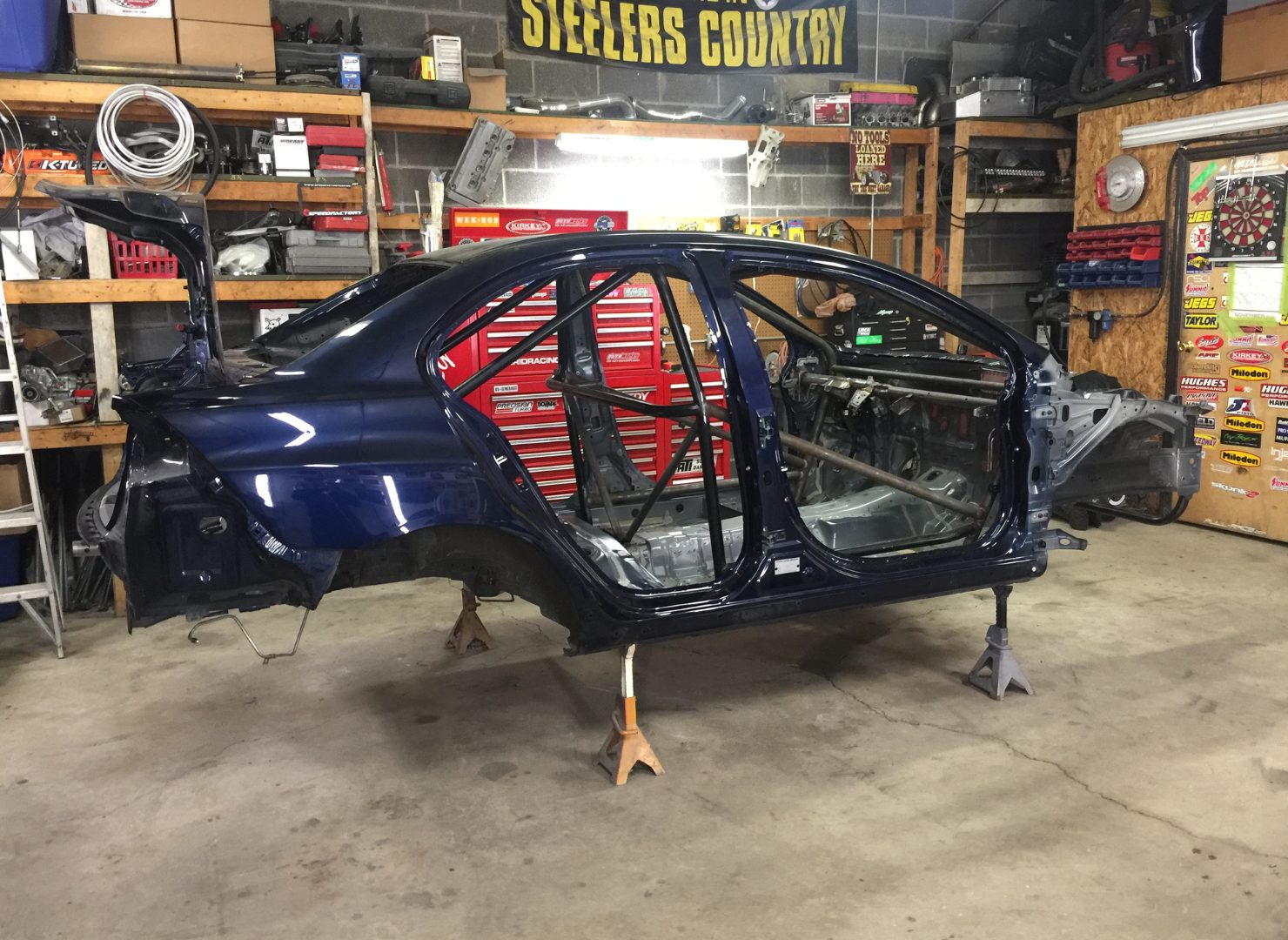 Dark blue Evo X shell with a red roll cage in the shop