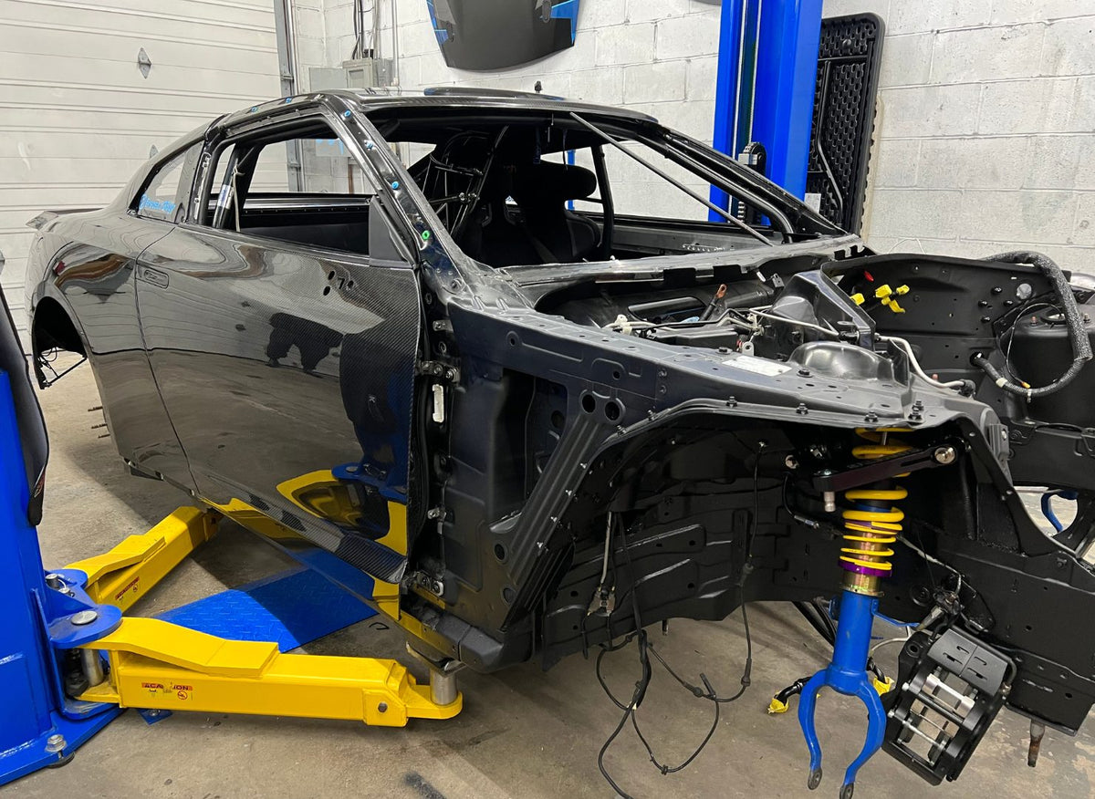 Stripped R35 GTR chassis on a lift during the drag-car build
