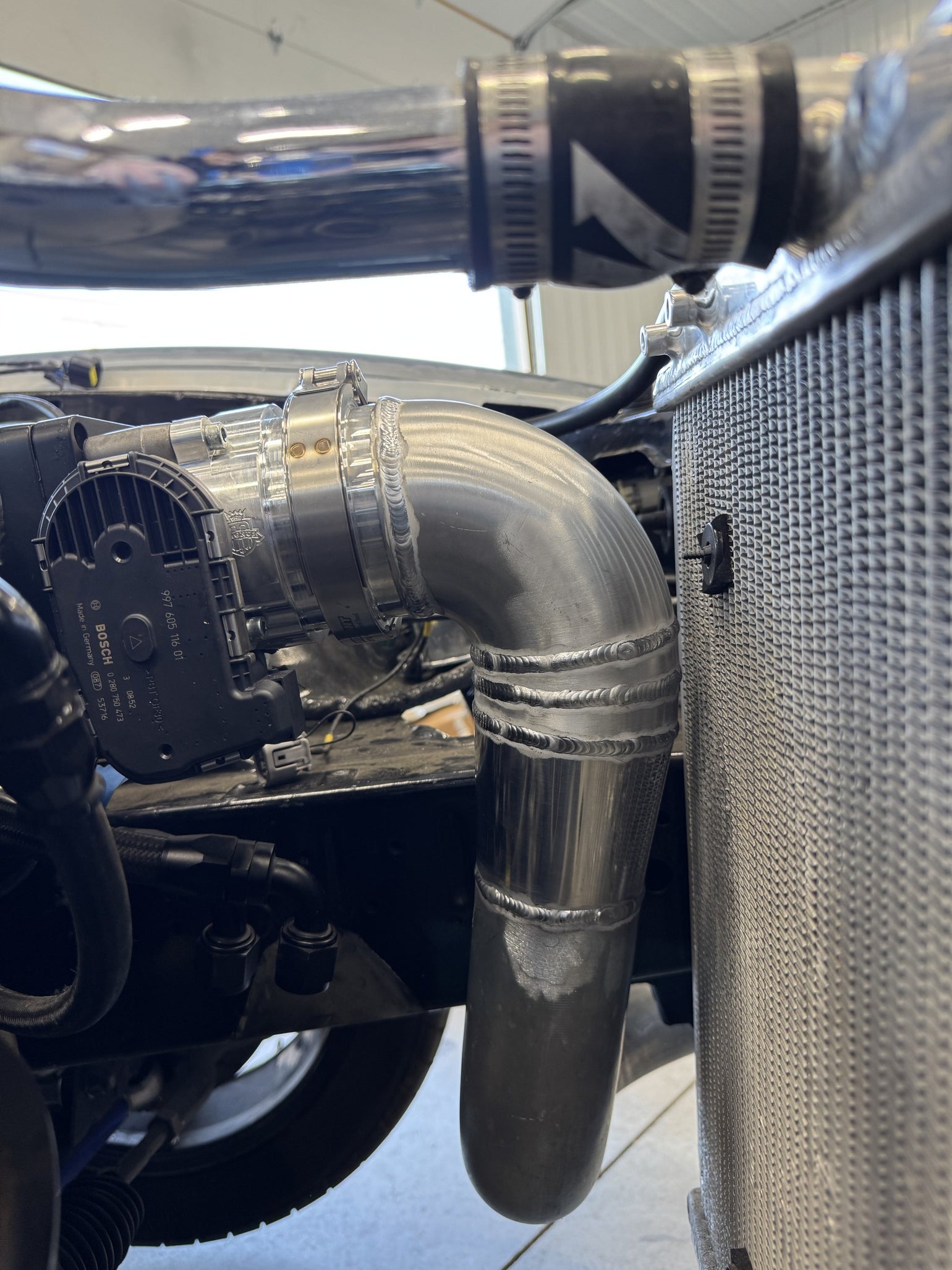 Fabricated charge pipe installed beside the radiator on an MK4 Supra